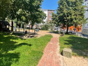 einen Backsteinweg in einem Park mit Bäumen und Bänken in der Unterkunft Lebendige Stadtwohnung in Stadtnähe in Bremerhaven