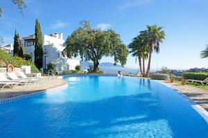 a large blue swimming pool with palm trees and a house at Apartment Jacarandas de Elviria in Marbella