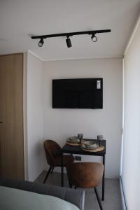 a room with a table and a tv on the wall at Departamento Parque O'higgins, Movistar Arena in Santiago