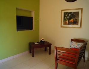 Sala de estar con silla, mesa y TV en La Residencia Inn, en Jinotepe