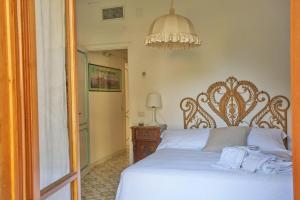 una camera da letto con un letto bianco e un lampadario di Villa D'apuzzo nel cuore di Positano a Positano