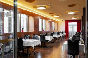 a dining room with white tables and black chairs at Hotel Prunk in Sežana