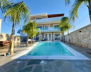 a swimming pool in front of a house with palm trees at Odysseia Stay Pool & Private Jacuzzi 2min Beach in Kremasti