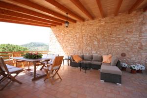 a patio with a couch and a table and a stone wall at Can Ramon in Caʼs Concos