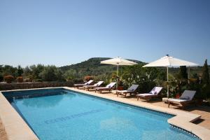 a swimming pool with chairs and umbrellas at Can Ramon in Caʼs Concos