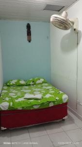 a bedroom with a bed with a green comforter at Alojamiento LETICIA in Leticia