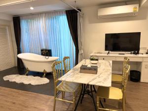 チェンマイにあるNidhra Lanna Hotel Chiang Maiのバスルーム(テーブル、バスタブ付)、テレビが備わります。