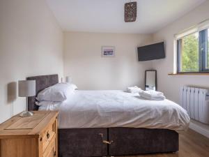 a bedroom with a large bed with a wooden table at Cabin W Hot Tub, Outdoor Dining In National Park in Otterburn