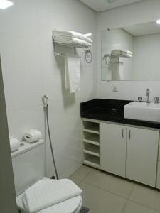 a white bathroom with a toilet and a sink at Garvey - flat 638 in Brasilia
