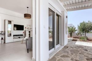 a living room with white walls and a large window at Sea view - Villa Emmanouella in Makry Gialos