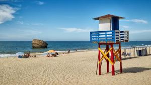 een strandwachttoren op een strand met mensen op het strand bij Tu casa en Doñana in Matalascañas