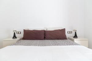 a white bedroom with a large white bed with two lamps at Sopranis by Gades Gestión in Cádiz