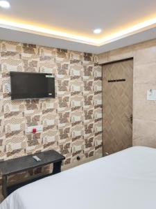 a bedroom with a tv on a brick wall at Hotel Shyama Palace in Jamshedpur
