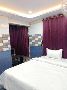a bedroom with a large white bed with purple curtains at Hotel Shyama Palace in Jamshedpur