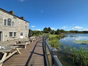 a row of picnic tables on a boardwalk next to a river at Lakeside 18 in Carnforth