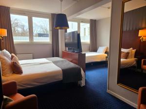 a hotel room with two beds and a mirror at Vänerport Stadshotell i Mariestad in Mariestad