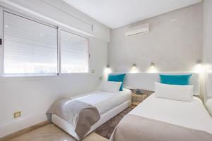 two beds in a white room with blue accents at Urban Chic 2 bedrooms in Utimate City Center in Marrakech