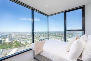 1 dormitorio con cama blanca y ventanas grandes en 2BR Apartment, Panoramic 180 Degrees Views on 52nd Floor, en Melbourne