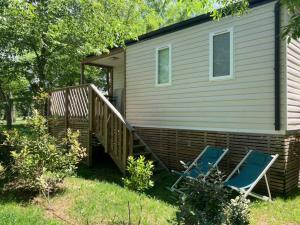 a house with a deck and two chairs in the yard at Camping 3 étoiles - ccaiiah in Ruoms