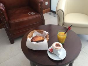 a table with a cup of coffee and a croissant and a drink at Hotel La Regence in Villefranche-sur-Mer
