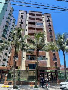 a tall building with palm trees in front of it at APÊ VISTA MAR, 20mts DA PRAIA, ESPAÇOSO E ACONCHEGANTE-56m2- WIFI- 1 DORM-ELEVADOR- 6 PESSOAS in Praia Grande