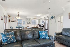a living room with a leather couch and a kitchen at KD2033- Ocean Breeze in Kill Devil Hills