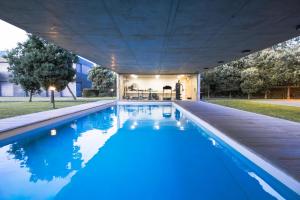 an indoor swimming pool with blue water underneath a building at Emerald Wave Oasis in Ponta Delgada