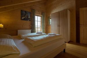 a bedroom with two beds in a wooden room at Feriendorf Koralpe Chalet Edelweiss in St. Gertraud