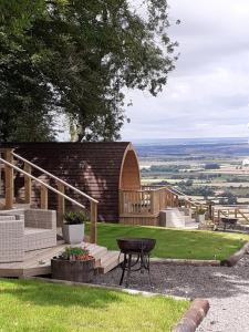 a patio with a table and a wooden building at Glamping Pod - Vale View in East Heslerton