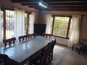 Un comedor con mesa y sillas y ventanas. en Chalet con Piscina exclusiva en el centro de Mar de las Pampas, en Mar de las Pampas