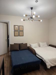 a bedroom with a bed and a couch and a chandelier at Very cozy 2 Room apart NEW GUDAURI, LOFT 2, apt 223 in Gudauri