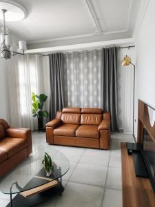 Una sala de estar con un sofá y una mesa de cristal. en Maison Nouvelle Route Carrossel, en Yaoundé