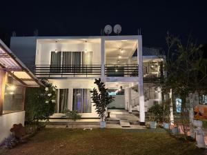 a white house with a balcony at night at Shimada Villa in Bentota