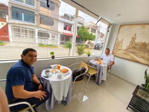 two men sitting at tables in a restaurant at Hotel Begonias in Chiclayo