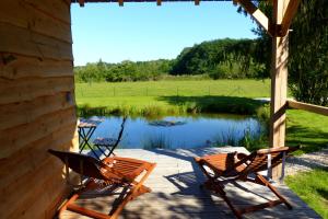 two chairs sitting on a porch next to a pond at Le bain de campagne in Montereau