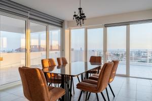 a dining room with a table and chairs and windows at Penthouse with outdoor hottub in Limassol +43 photos