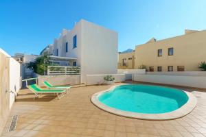 - une piscine sur une terrasse avec 2 chaises et un bâtiment dans l'établissement Residence Blu Mare, à San Vito Lo Capo