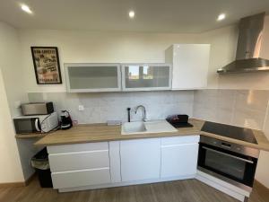 a kitchen with white cabinets and a sink at La Maison 19 T2 Lens centre in Lens +3 photos