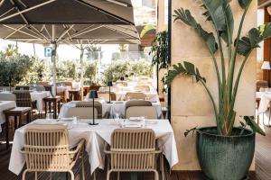 a restaurant with white tables and chairs and a potted plant at Real Marina Hotel & Spa in Olhão