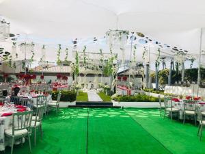 a banquet hall with white tables and chairs and green floor at Hamburg Home Lodge in Tema