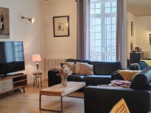 a living room with a couch and a tv at Duplex'po in Dinan
