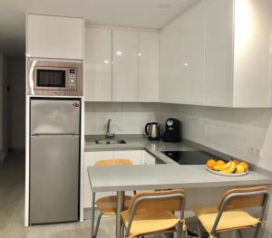 a kitchen with white cabinets and a table with a bowl of fruit at Olimpus Apart Leasure in Costa de Adeje