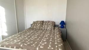 a bed in a small room with a blue lamp at Appartement Grand Large - 3 pièces - 5 couchages in Le Barcarès