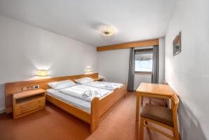 a bedroom with a bed and a desk and a window at Villa Pana in Santa Cristina Gherdëina