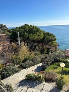a stone path with flowers and the ocean in the background at Mare e Relax - Il Villino ai Tre Ponti - Monolocale in Sanremo