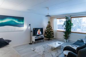 a living room with a christmas tree and a couch at Arctic Aurora Villa with Sauna - Northern Lights and Adventures in the Hometown of Santa Claus, Rovaniemi in Rovaniemi
