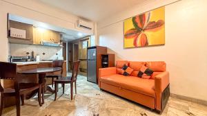a living room with an orange couch and a kitchen at Suite Apartment Ragam Citra Property Legian in Seminyak