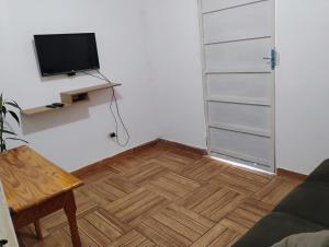 a living room with a tv and a wooden floor at Studio próximo às Cataratas do Iguaçu in Foz do Iguaçu