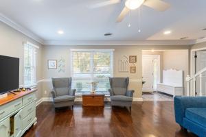 a living room with two chairs and a tv at 8-Guest Cozy Escape with Fire Pit & Hot Tub! in Pawleys Island
