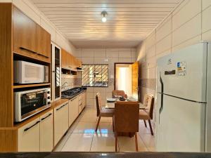 a kitchen with a table and a refrigerator at Casa 3quartos sinuca prox Paraguai e Itaipu in Foz do Iguaçu